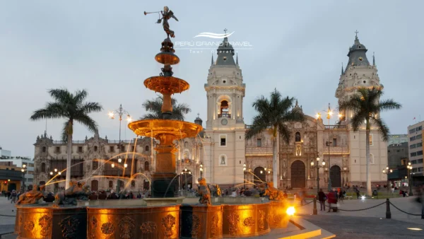 Fuente de la Plaza Mayor de Lima iluminada al atardecer, con la Catedral de Lima y palmeras en el Centro Histórico al fondo