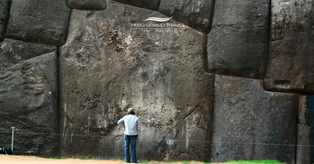 Sacsayhuamán Perú: 7 Secretos de la Gigante Fortaleza Inca 1 Turista de pie junto a los enormes muros de piedra de Sacsayhuamán Perú