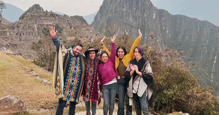 Qué hacer en Cusco 4 Días: Todo lo que necesitas saber para una Experiencia Única 5 Amigos posando para la foto de fondo, la montaña de Machu Picchu y los espacios arqueológicos de fondo