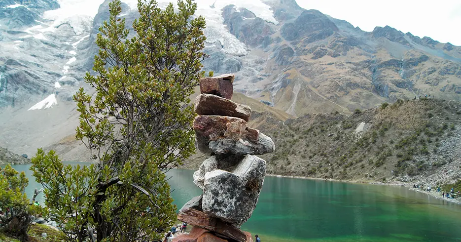 Apachetas en la laguna humantay cusco y al fondo se ve la laguna humantay turquesa y las montañas