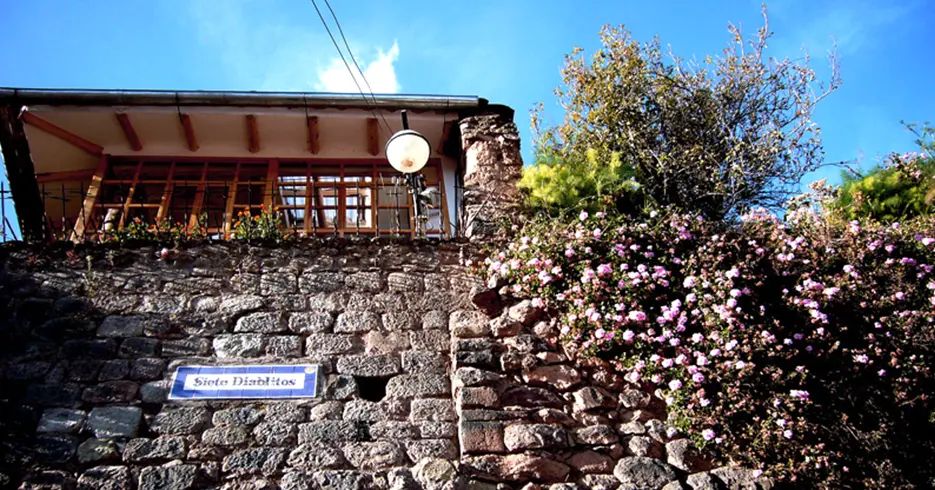 Viaja sin estrés: los mejores paquetes turísticos Cusco 8 Calle siete diablitos en cusco, árbol con flores rosas hacia afuera y le cartel del nombre de la calle