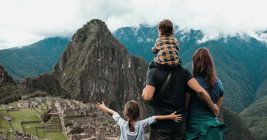 Familia de turistas en Machu Picchu, con dos niños pequeños, observando Machu Picchu y sus vestigios incas