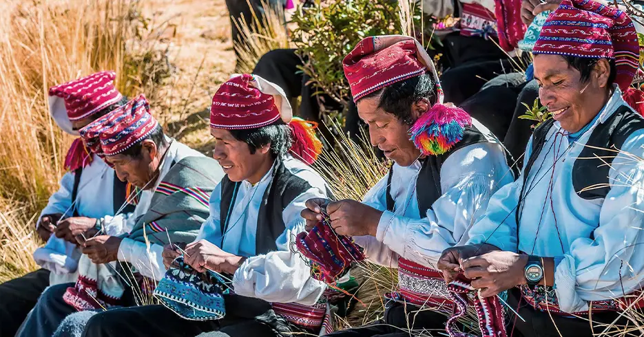 Hombres sonriendo y tejiendo sus textiles en la isla taquile en puno
