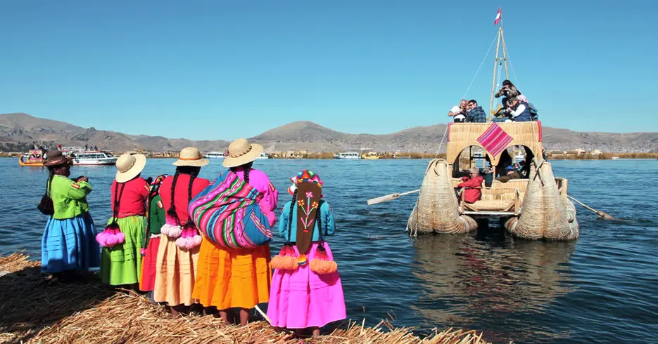 Los 10 Mejores Lugares Turísticos a Visitar en Cusco Perú 8 Mujeres de la isla de los uros despidiendo a los turistas que van en un barco de totora en el lago Titicaca en puno