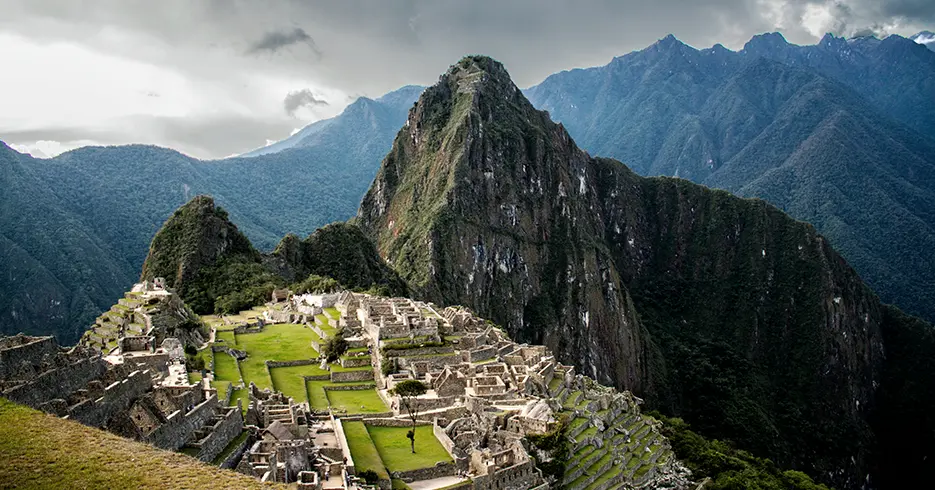 Cosas que hacer en Cusco: Lo mejor de la ciudad en un solo viaje 6 Vista de Machu Picchu, con sus estructuras de piedra rodeadas de montañas verdes y un cielo parcialmente nublado