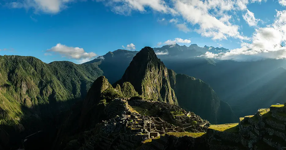 ¿Qué lugares puedo visitar en Perú? Maravillas naturales y culturales 3 Machu Picchu en cusco, rodeado de montañas y un cielo celeste con los vestigios incas en la parte baja