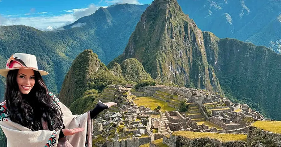 Perú en 10 días: Tu Guía a los mejores lugares 5 Turista sonriendo mostrando Machu Picchu, con un cielo celeste y rodeada de montañas, en la parte baja se ven los restos arqueológicos de la ciudad inca