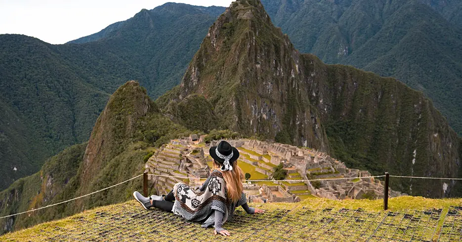 Mujer sentada en un mirador de Machu Picchu, aprovechando la mejor época para ir a Machu Picchu