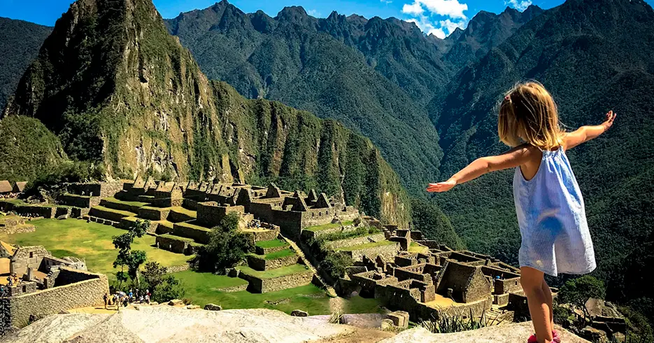 niña jugando en una piedra de machu picchu