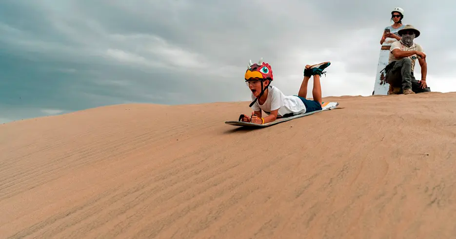 Todo lo que Tienes que Saber sobre Huacachina: Un Oasis en el Desierto 8 niño haciendo sandborading en las dunas de haucachina en ica
