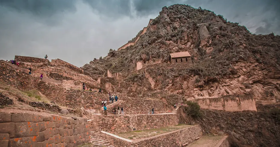 Sitio arqueológico de ollantaytambo, lleno de turistas con una montaña rocosa, lugares turisticos cerca de machu picchu