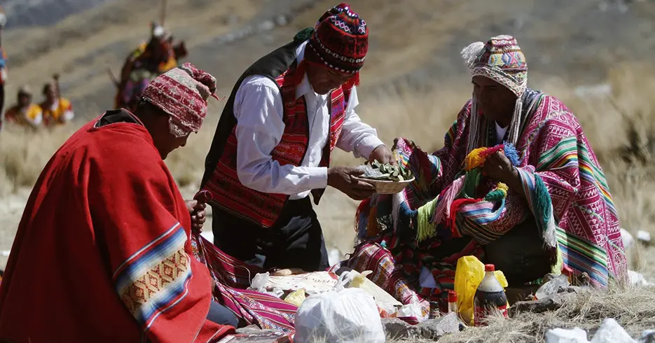 Cosas que hacer en Cusco: Lo mejor de la ciudad en un solo viaje 8 Tres hombres realizando una ceremonia en honor a la Pachamama, rodeados de paisajes y vestidos con ropa típica de Perú