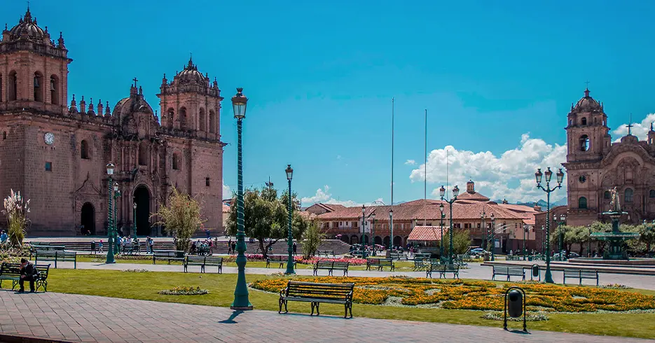 Perú en 10 días: Tu Guía a los mejores lugares 1 Plaza de armas de Cusco con un cielo celeste despejado, bancos en la plaza, se ven las dos iglesias, catedral y compañía de Jesús