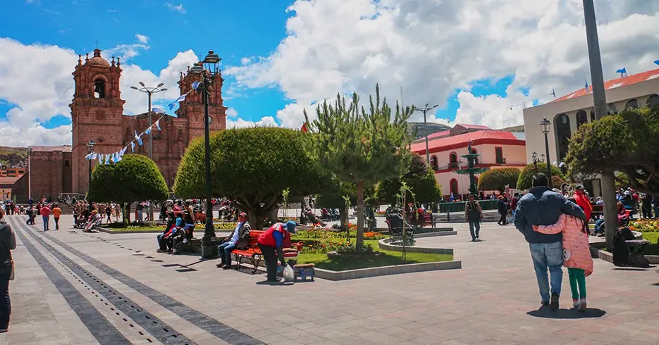 Lugares para visitar en Puno Perú: Explora lo Mejor con Nosotros 5 lugares para visitar en puno peru Plaza de armas de puno, catedral de puno de fondo con bastantes árboles alrededor de la plaza y un cielo celeste. Varias personas caminando y sentadas.