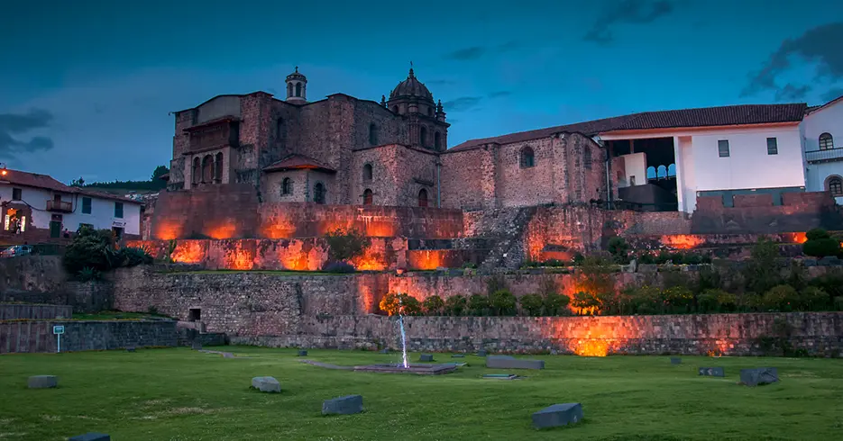 qoricancha o el templo del sol en cusco, vista del jardín regando agua y las luces alumbrando el templo.