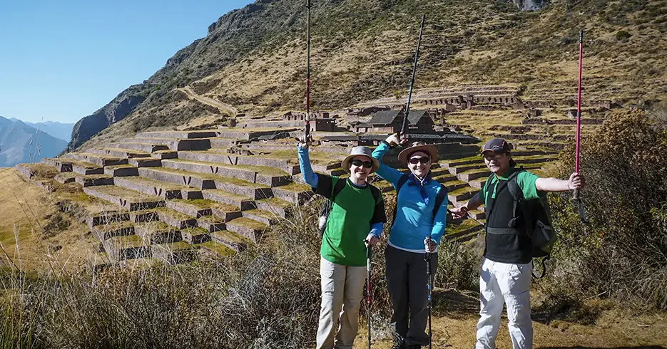 Turistas posando en la ruta huchuy qosqo, con sus bastones de trekking y vistas de paisajes y vestigios incas