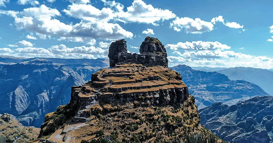 Trekking en Perú, waqrapukara, sitio arqueológico en forma de cuerno y vistas de grandes montañas y un cielo celeste