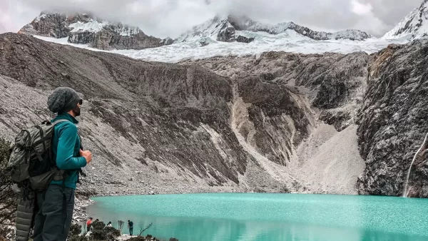 Turista en Huaraz en la laguna 69, una laguna turquesa y nieve en la parte de arriba en las montañas
