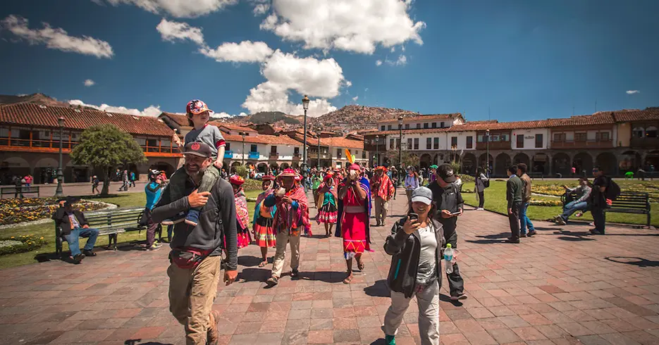 ¿Qué Ver en Perú 9 Días? Los Imperdibles del País 1 Turistas caminando por la plaza de armas de cusco y personas locales vestidas con trajes típicos, haciendo como un teatro