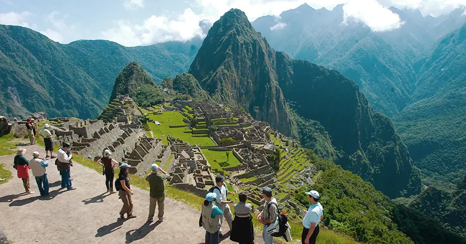 Turistas en el santuario de Machu Picchu, con vista hermosa de la ciudadela inca