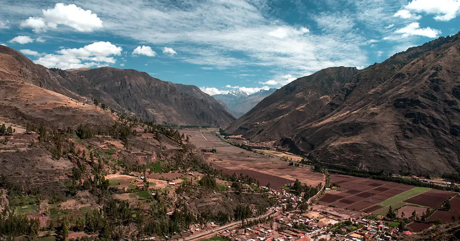 Viaje a los Andes en 11 días: Lugares impresionantes que debes conocer 2 Vista del valle sagrado en cusco, con paisaje lleno de montarlas y árboles, un cielo despejado y celeste