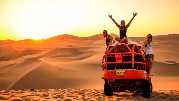 Viaje a Ica: lugares top que valen la pena conocer 9 viaje a ica - turistas en huacachina encima de un buggie con un atardecer rojo y naranja en el fondo