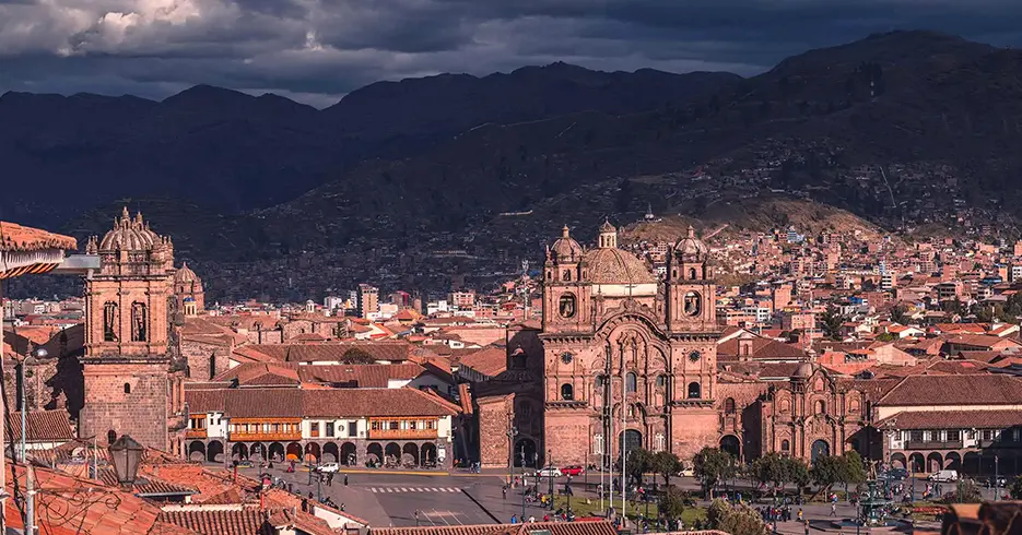 Viaje a los Andes en 11 días: Lugares impresionantes que debes conocer 1 Plaza de armas de cusco, de fondo muchas casas y la vista de montañas y de la iglesia de la catedral y la compañía de Jesús
