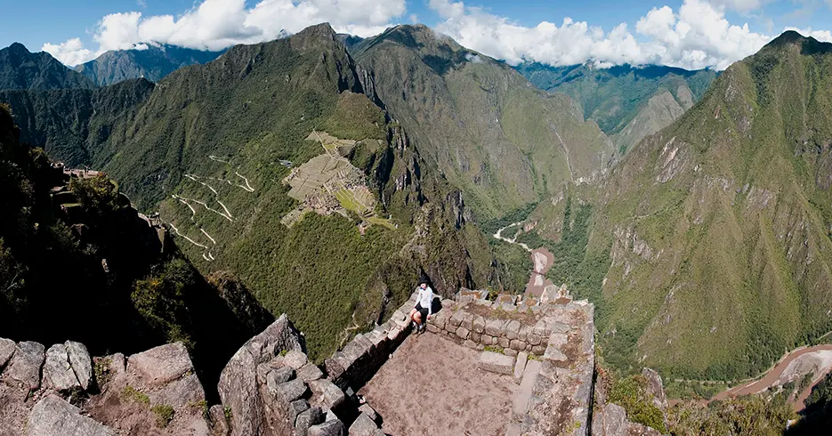 Turista posando en una de las vistas de huayna picchu, en la parte baja se observa la ciudadela inca, y el río urubamba